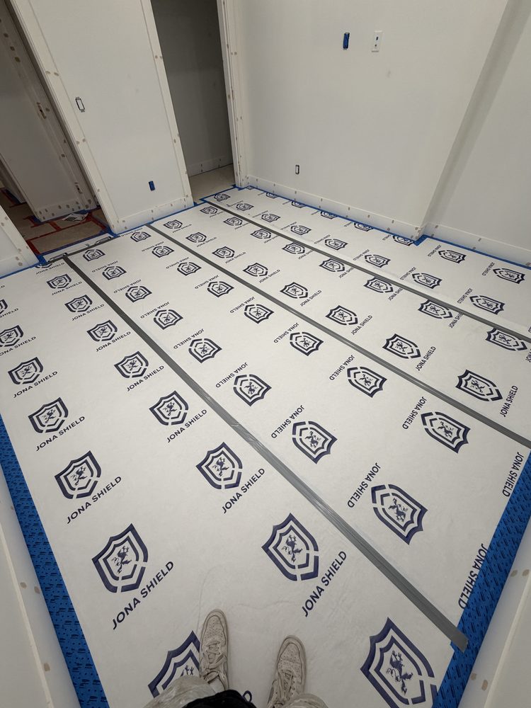 Taped seams and masked baseboards over Jona Shield surface protection in a hallway